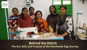 A group of six female artisans smiling together behind a white Jack sewing machine, showcasing the community behind the handmade bag journey.