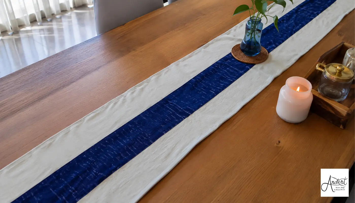 Cream and blue canvas table runner set on a wooden dining table alongside home decor accessories.